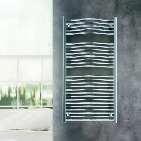 Shiny chrome towel radiator mounted on grey wall in modern bathroom.