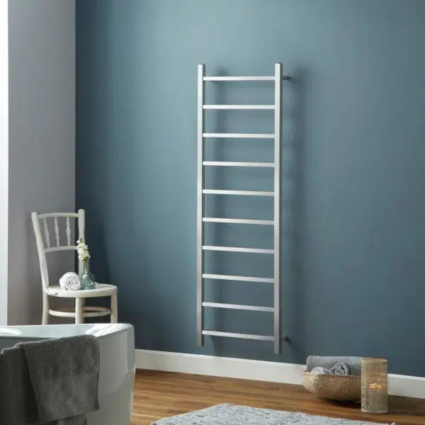 Radiator towel rail, modern silver heated towel rack in blue bathroom wall, stylish heating solution for home, space-saving bathroom decor, towel warmer installation.
