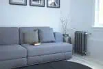 Modern living room with gray sofa, minimalist decor, and radiator heating system.
