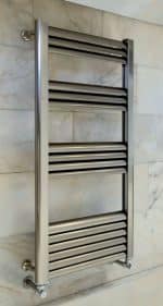 Polished stainless steel towel radiator for bathrooms, wall-mounted, modern heating solution.