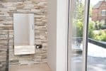 Modern electric radiator with sleek design mounted on stone feature wall in a bright, contemporary home interior.