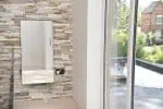 Modern electric radiator with sleek design mounted on stone feature wall in a bright, contemporary home interior.
