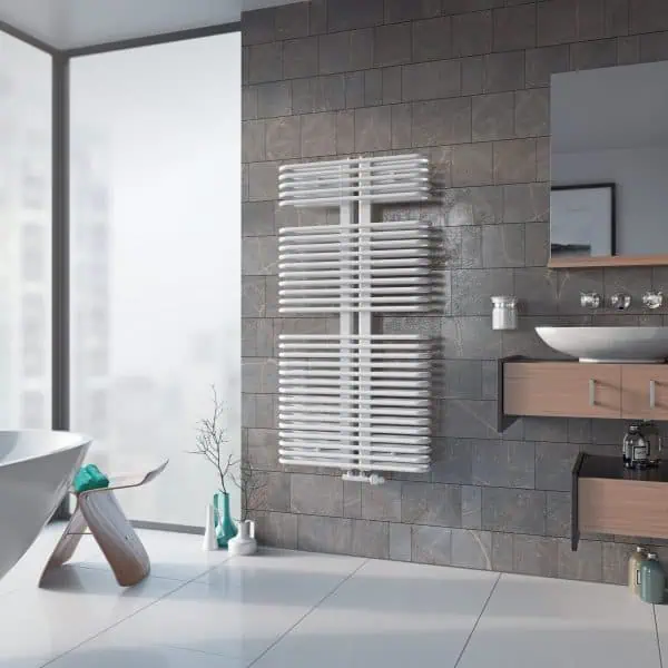 Modern white heated towel rail in a stylish bathroom with grey tiled wall and wooden cabinetry.