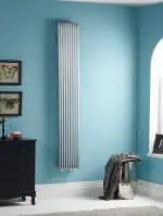 Vertical modern chrome radiator in a bright blue living room.