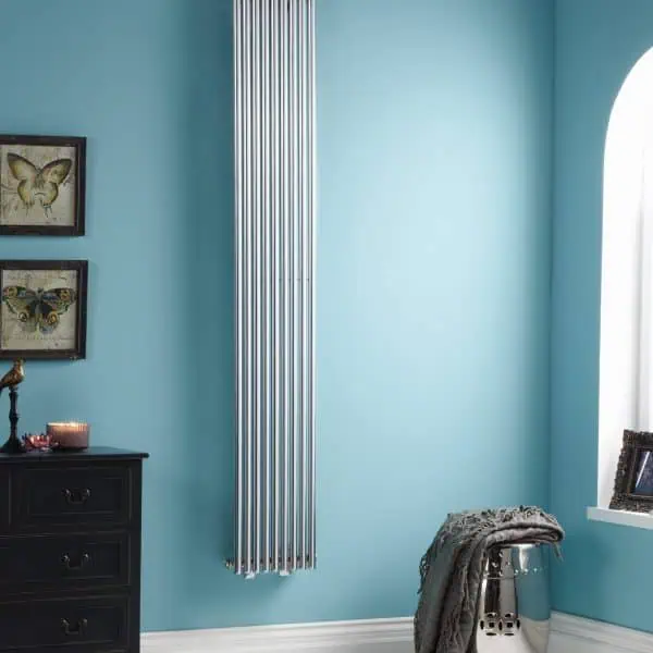 Vertical modern chrome radiator in a bright blue living room.