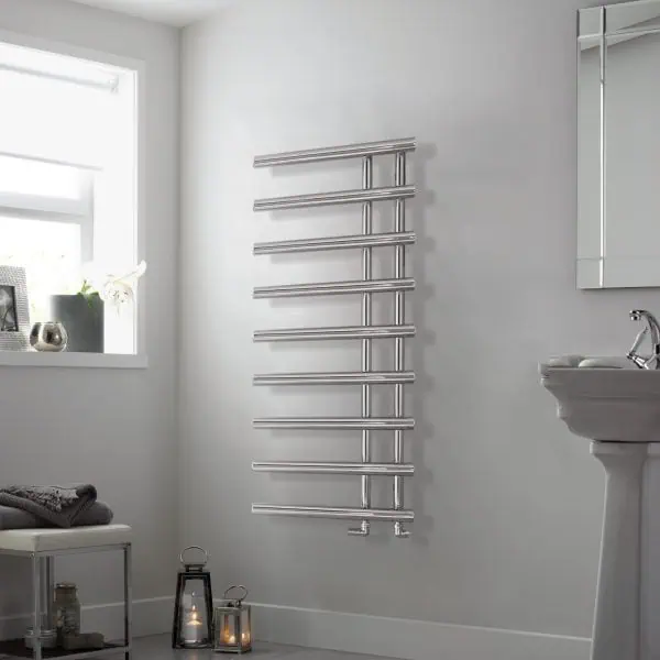 Polished stainless steel heated towel rail in a modern bathroom setting.