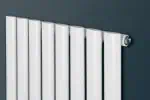 Modern white radiator mounted on a gray wall, energy-efficient heating solution.