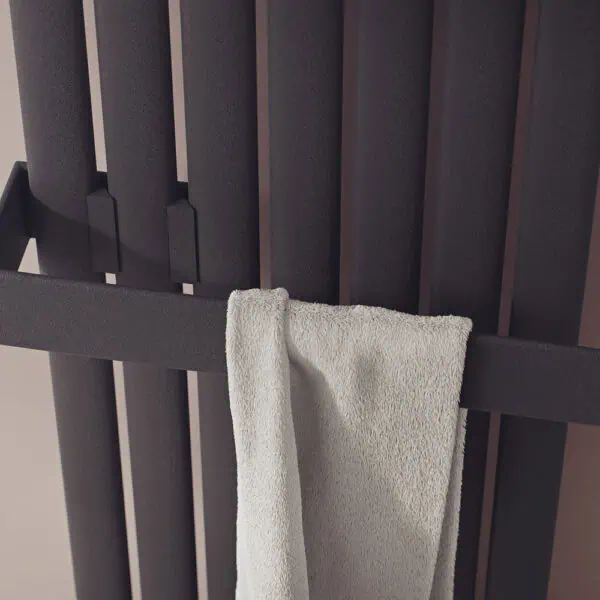 Black radiator towel warmer with a white towel hanging, modern home heating solution.