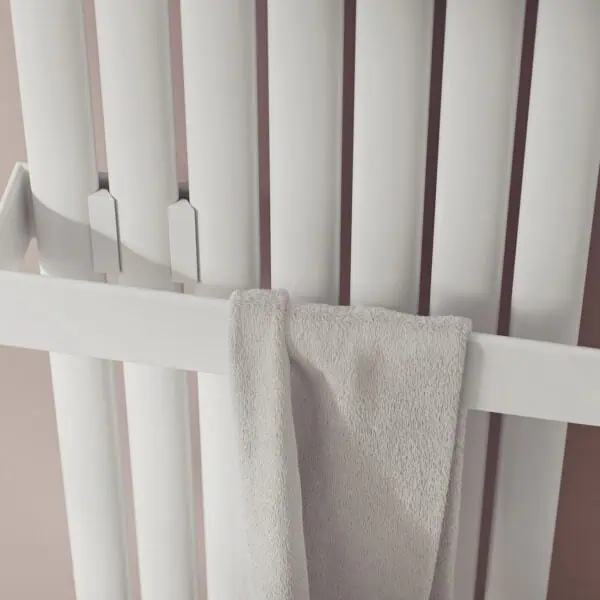 Radiator with towel rail in modern interior, white heating panel with towel hanging, home heating and bathroom radiator, close-up image.