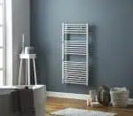 Radiator towel rail in modern bathroom with blue wall and wooden floor.