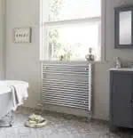 Radiator towel rail in a modern bathroom with natural light and decorative accessories.
