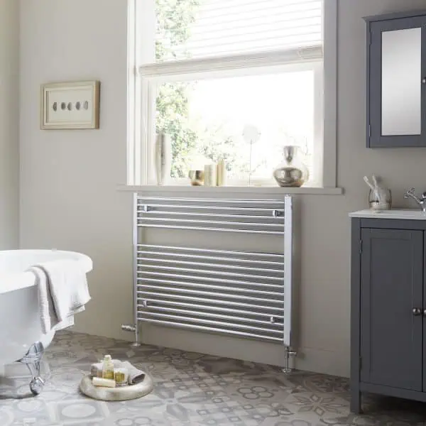 Radiator towel rail in a modern bathroom with natural light and decorative accessories.