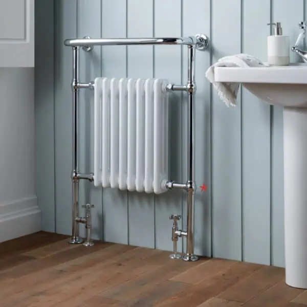 Radiator and piping installation in a modern bathroom, featuring chrome fixtures and wall paneling.