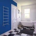 Chrome towel radiator in modern bathroom with clawfoot bathtub and checkered flooring.