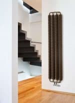 Industrial radiator heater with modern staircase in contemporary home setting.