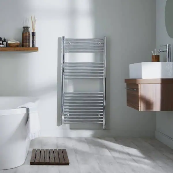 Chrome towel radiator in modern bathroom with wooden accents and white bathtub.