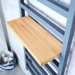 Natural wood shelf with blue metal frame in modern storage unit.