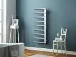Radiator towel warmer in modern bathroom with blue wall and wooden flooring, stylish heated towel rail.
