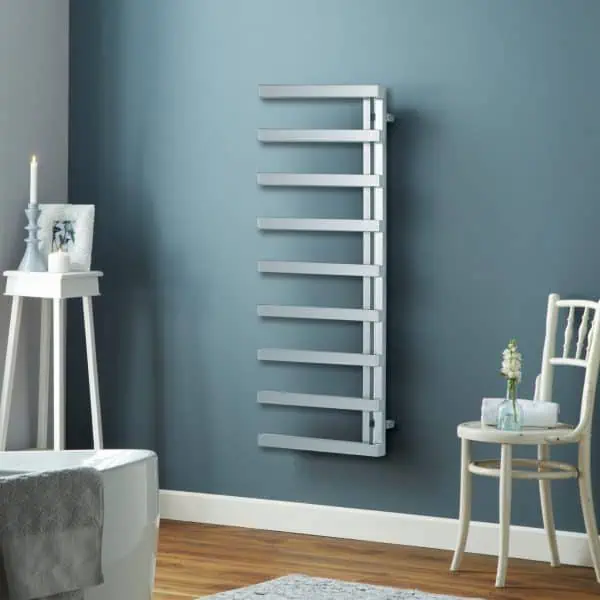 Radiator towel warmer in modern bathroom with blue wall and wooden flooring, stylish heated towel rail.