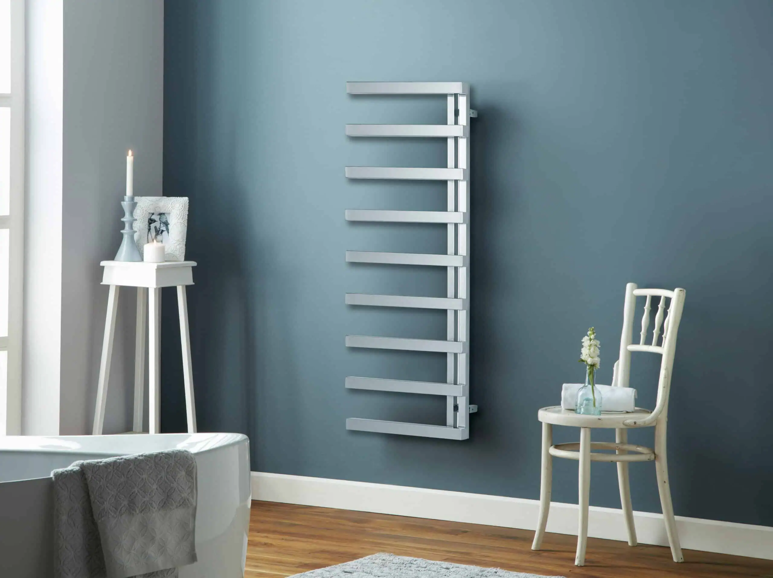 Soho-TR-127006-1245x500-rgb-scaled-2.jpg Radiator towel warmer in modern bathroom with blue wall and wooden flooring, stylish heated towel rail.