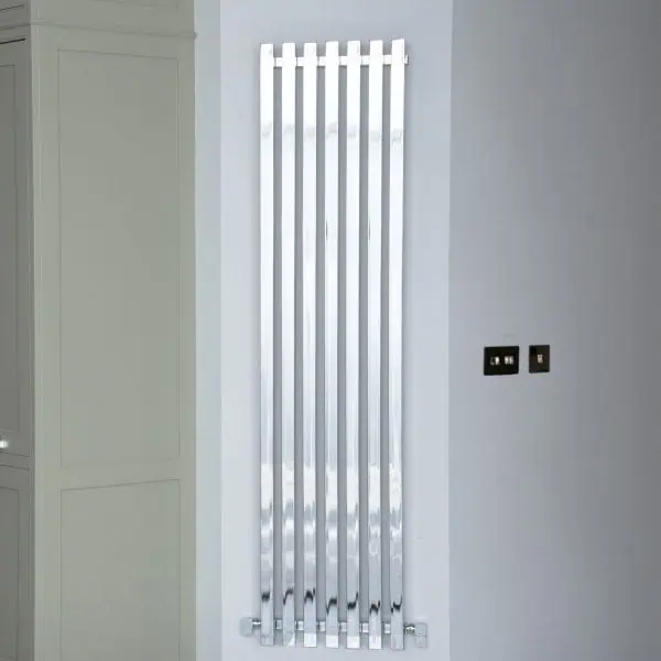 Polished chrome contemporary vertical radiator in modern interior setting.