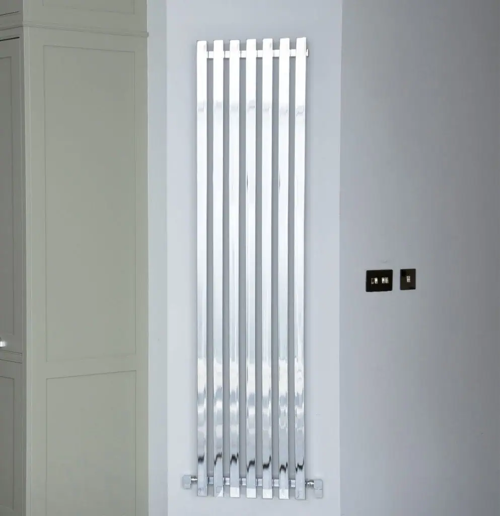 Shiny modern vertical radiator in a contemporary home decor setting.