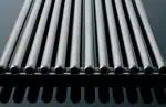 Shiny stainless steel rods arranged parallel on a black rack for industrial use.