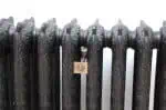 Ornate black cast iron radiator with locking mechanism for secure heating.