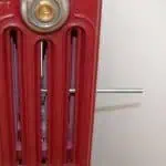 Highly detailed close-up of a red industrial radiators with metal screws and vents for heating systems.