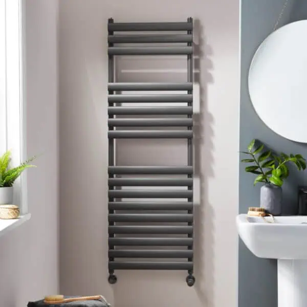 Wall-mounted heated towel rail in modern bathroom, sleek black finish, space-saving design for warmth and towel drying.