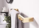 Polished gold towel holder with gray towel in modern bathroom decor.
