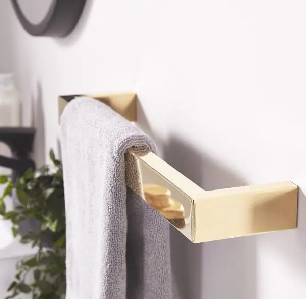 Polished gold towel holder with gray towel in modern bathroom decor.