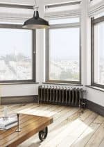 Bright modern interior with large windows, radiator, wooden flooring, and industrial-style pendant light.