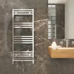 Modern chrome towel radiator in a stylish bathroom with marble wall tiles.