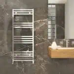 Modern chrome towel radiator in a stylish bathroom with marble wall tiles.