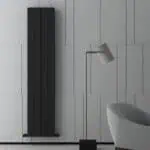 Modern black vertical radiator in minimalistic interior setting.