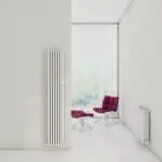 Radiator and modern lounge chair in minimalist white room with large window, bright natural light.