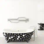 Colorful modern bathtub design with black, white, and metallic balloons, contemporary fixtures, and minimalist setting.