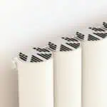 Modern white radiator with innovative black slatted design for efficient home heating.