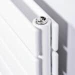 Radiator close-up with chrome screw and white panel, modern heating system design.