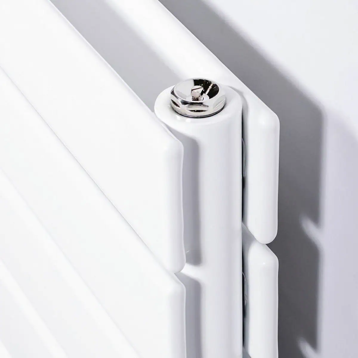 DQ-STRATA-H-D-W-CU00_1900__73602.1605274112.1280.1280__58086detay Radiator close-up with chrome screw and white panel, modern heating system design.