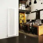 Radiator with white slats in modern office interior, working space with computers and decor elements.