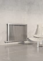 Sleek modern stainless steel radiator on a minimalist interior wall.