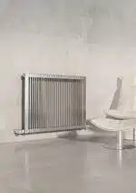 Sleek modern stainless steel radiator on a minimalist interior wall.
