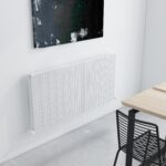 Modern white radiator mounted on a white wall in a minimalist interior setting.