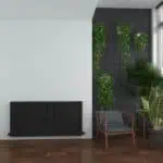 Modern interior with black radiator and lush green plant decor, stylish living space design.