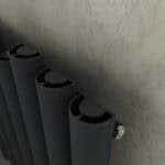 Black modern radiator with close-up view on textured wall.