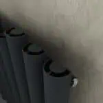 Black modern radiator with close-up view on textured wall.