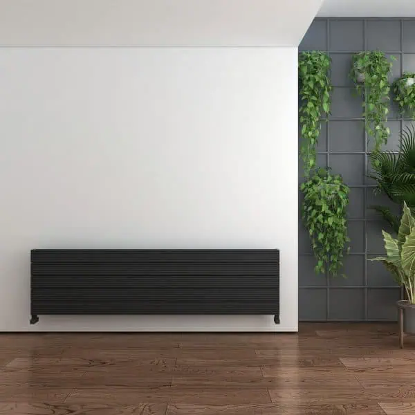 Modern sleek black radiator on a white wall with green plants in stylish interior setting.