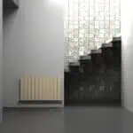 Modern interior with staircase, textured brick wall, and minimalist radiator.